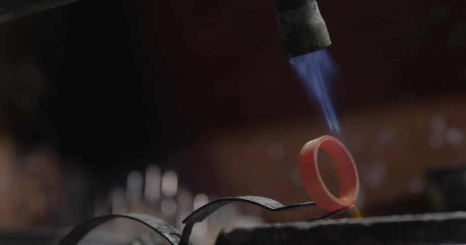 A flame from a torch burns a circle of metal red hot