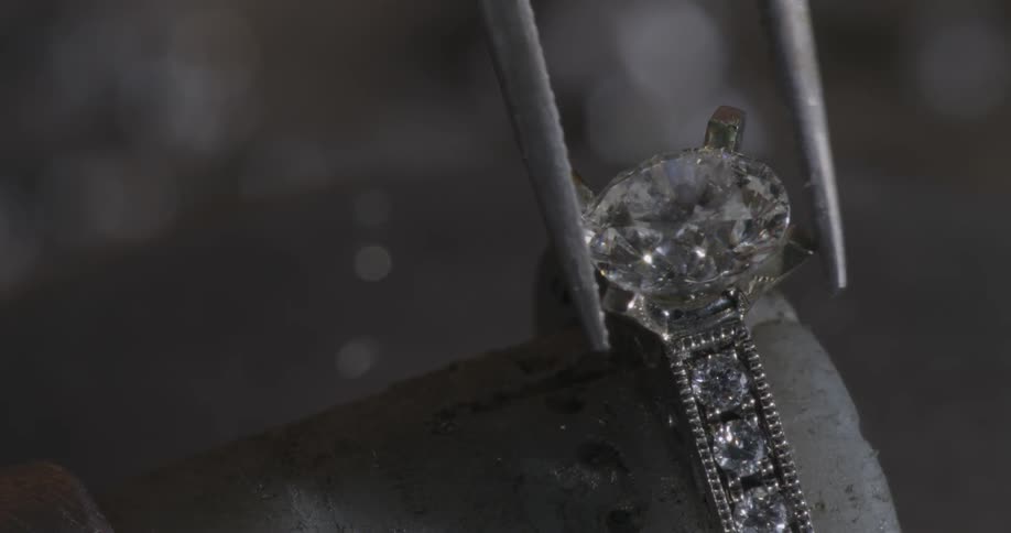 A gem being gently set into a ring with a tool