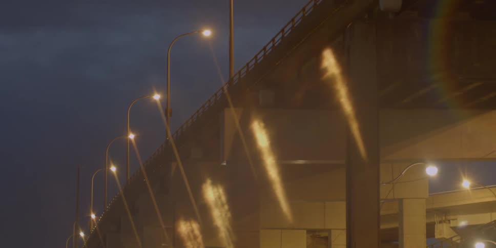 Street lamps shine down on a city bridge at night