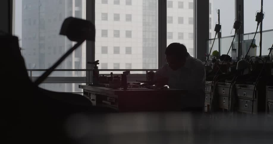 Man sits at work table using tools on a project