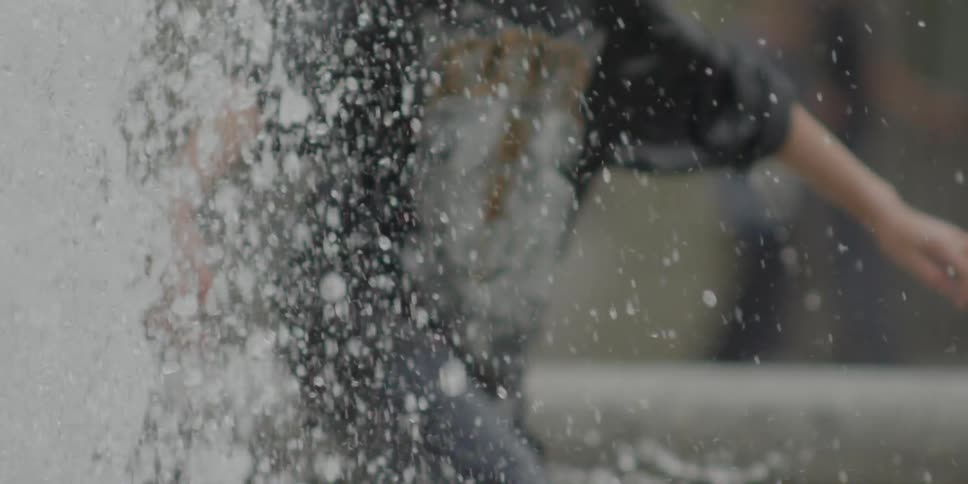 A young man walking through a water fountain