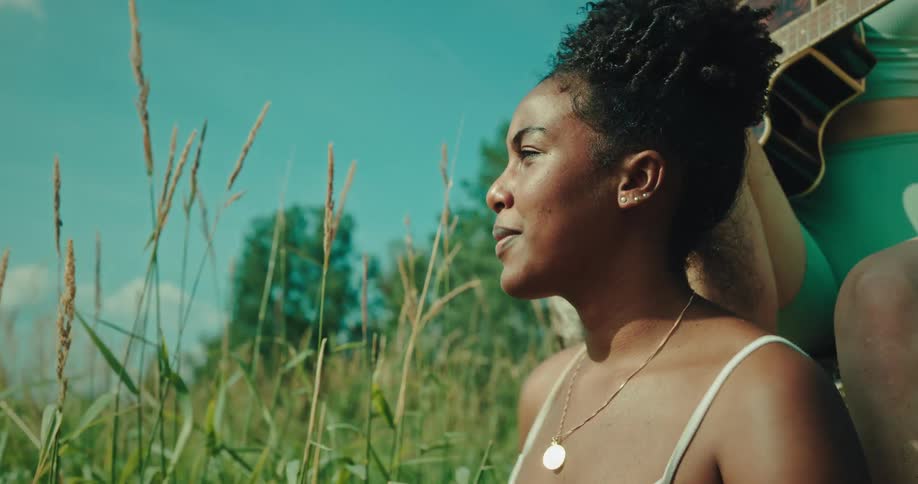 Portrait of a young woman enjoying music while another woman behind her plays the guitar