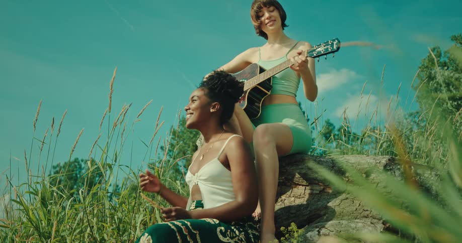 Friends in a field singing and playing guitar outdoors