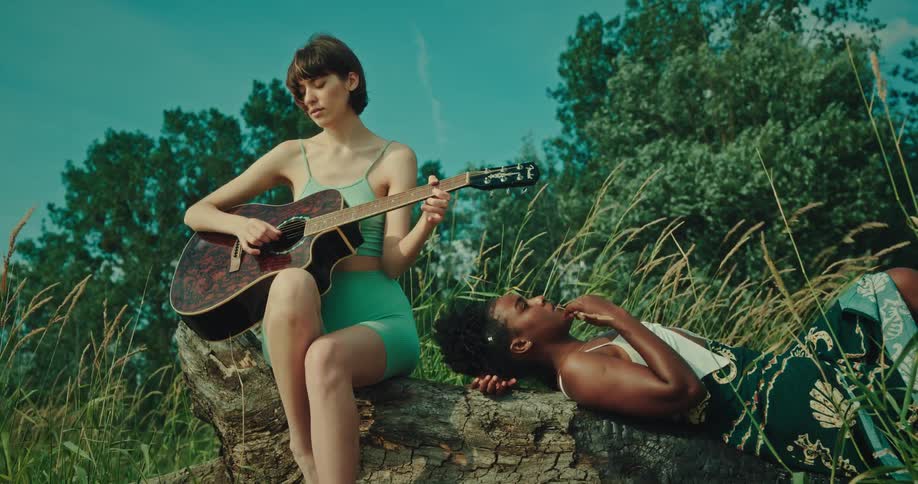 Singing friends playing guitar and singing in an outdoor field