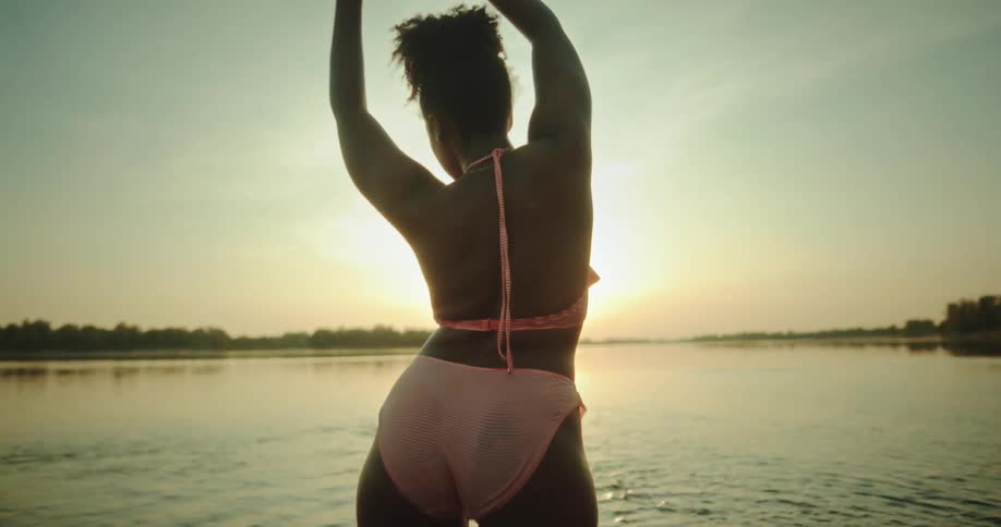 A woman walking by the sea at sunset