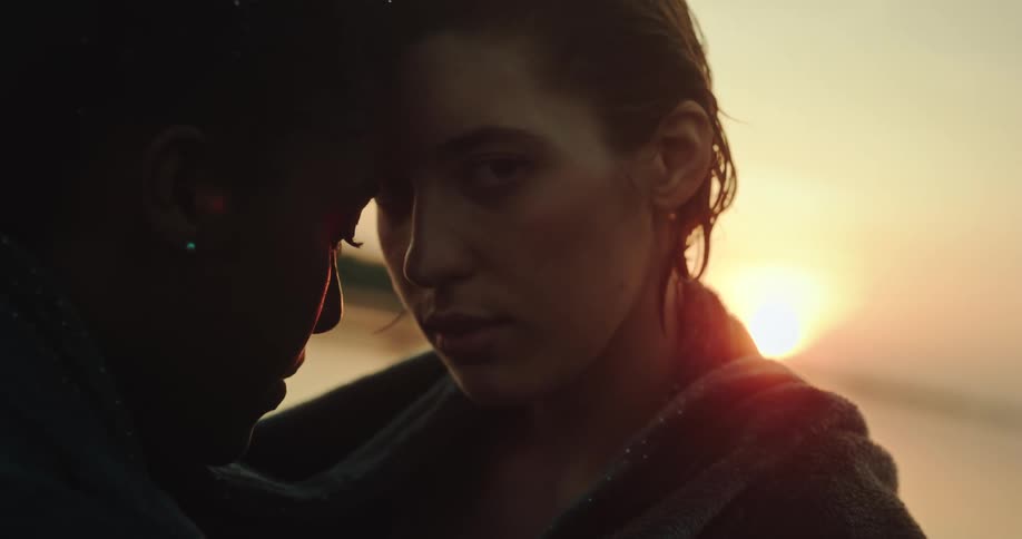 Two women wrapped in blanket hold each other at sunset