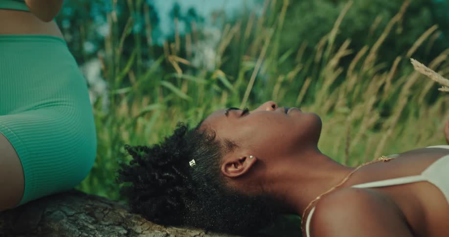 Woman playing the guitar with her friend lying beside her in a natural setting enjoying the moment
