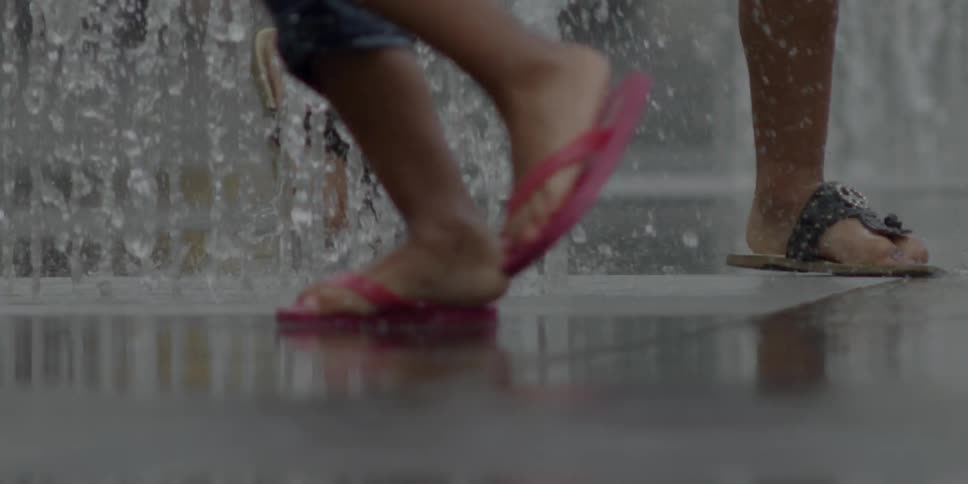Children run around a fountain shouting water out of the ground