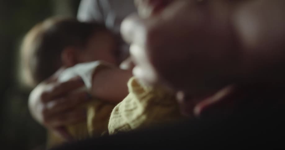 Mother breastfeeds infant as grandparent examines the babys feet