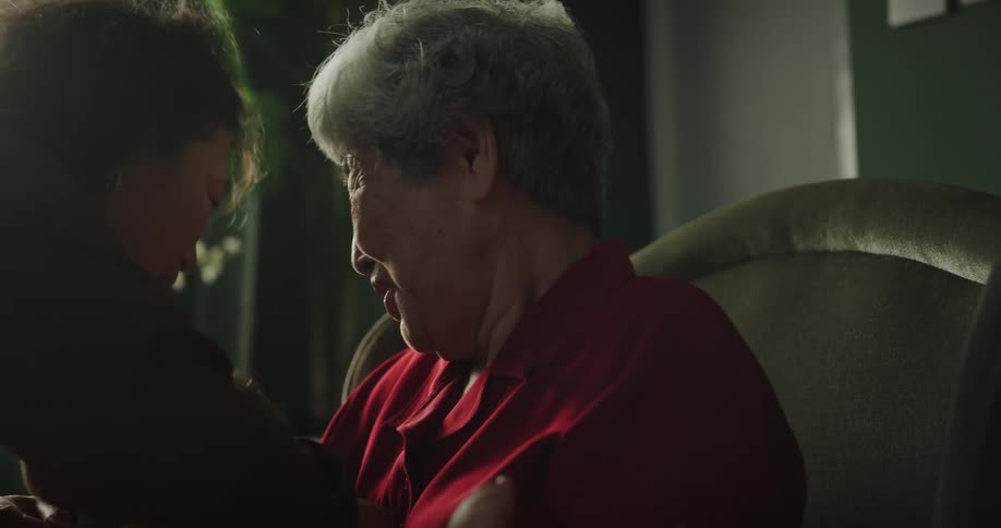 Grandmother holding her granddaughter who is crying and her mother picking her up
