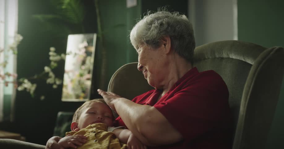 Grandmother holds sleeping grandchild and strokes the childs head