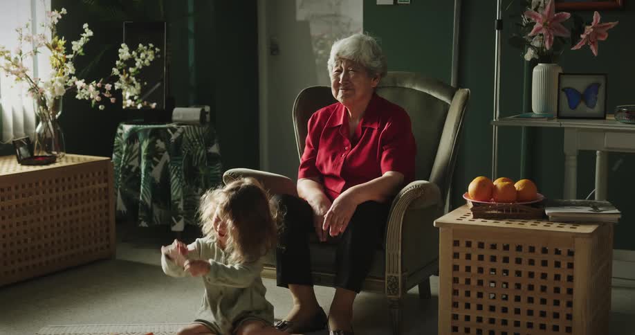 A grandmother watches her granddaughter brush her hair