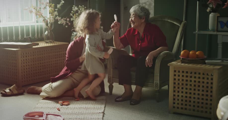 Two women playing and smiling with a toddler in a room at midday