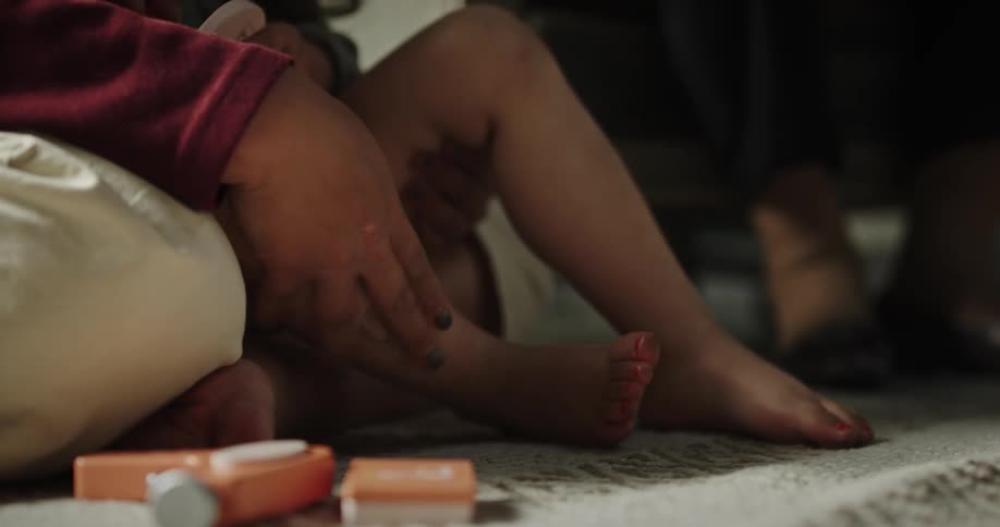 A parent playing with her kids legs
