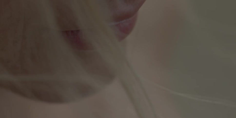 A woman's hair blows in front of her pink lips