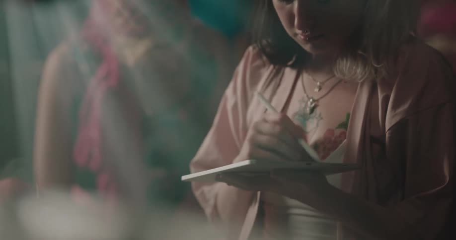 A woman with a heart tattoo drawing on a tablet