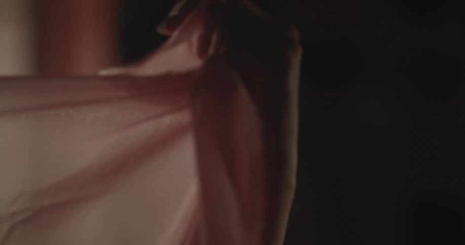 A woman holds up and stretches a piece of sheer fabric