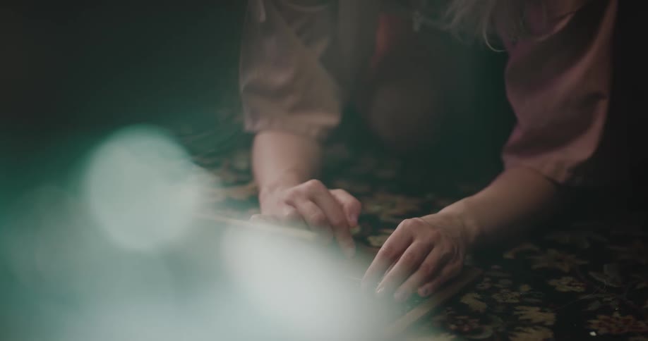 Portrait of a young woman squatting on the floor and typing on a laptop