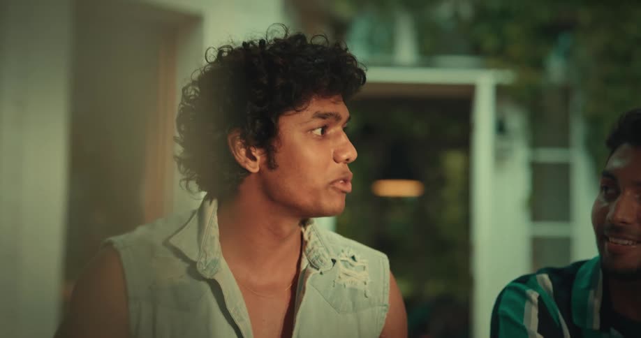 A young man smiles and gestures while talking to his friends