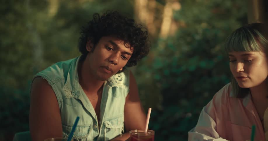 A group of young friends is sitting around a table and one of them is talking to the others