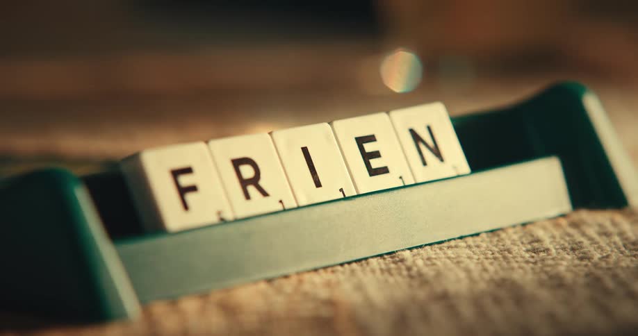 A person lines up scrabble tiles in a holder to spell a word