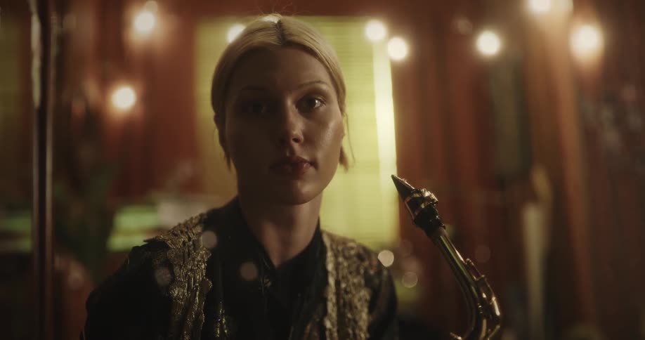 Lady smile after playing saxophone in a room at night
