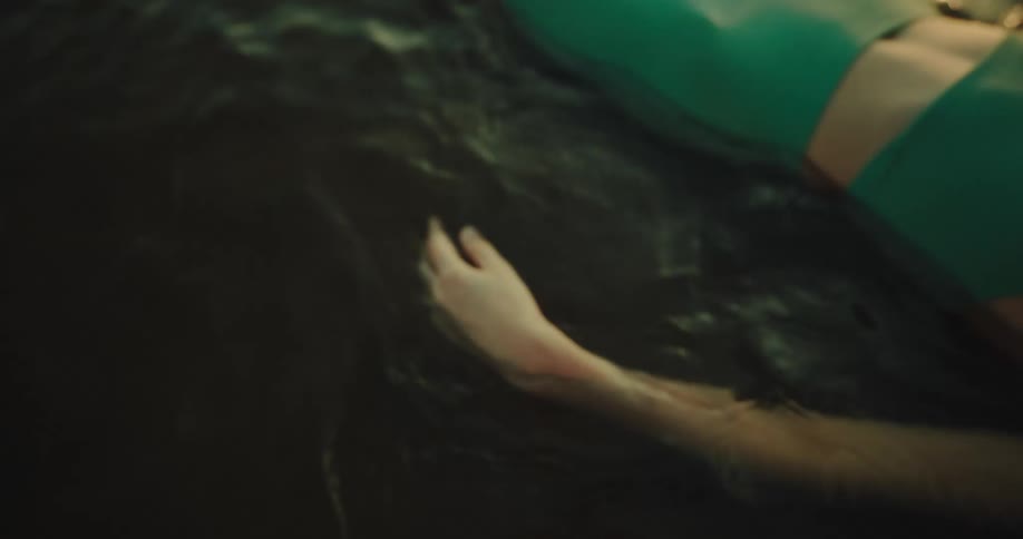 Closeup of the arm of a woman lying by a river with her hands moving