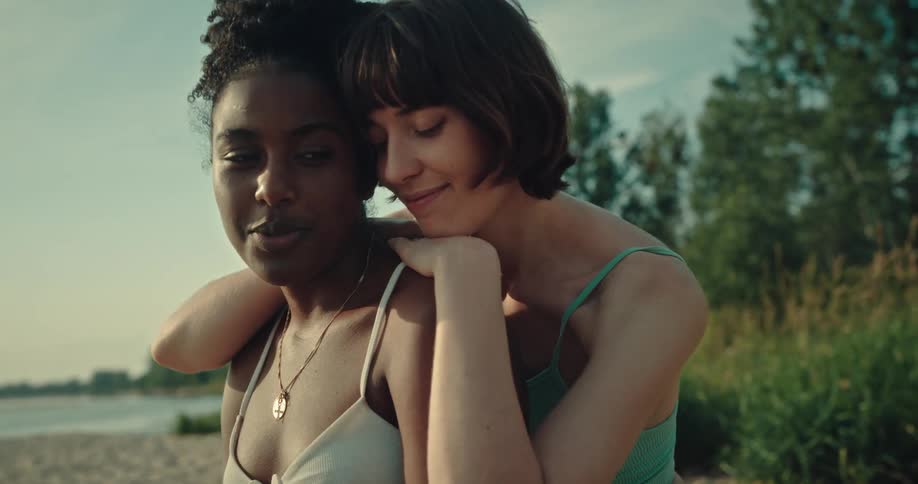 Woman affectionately hugging her friend on the sandy beach