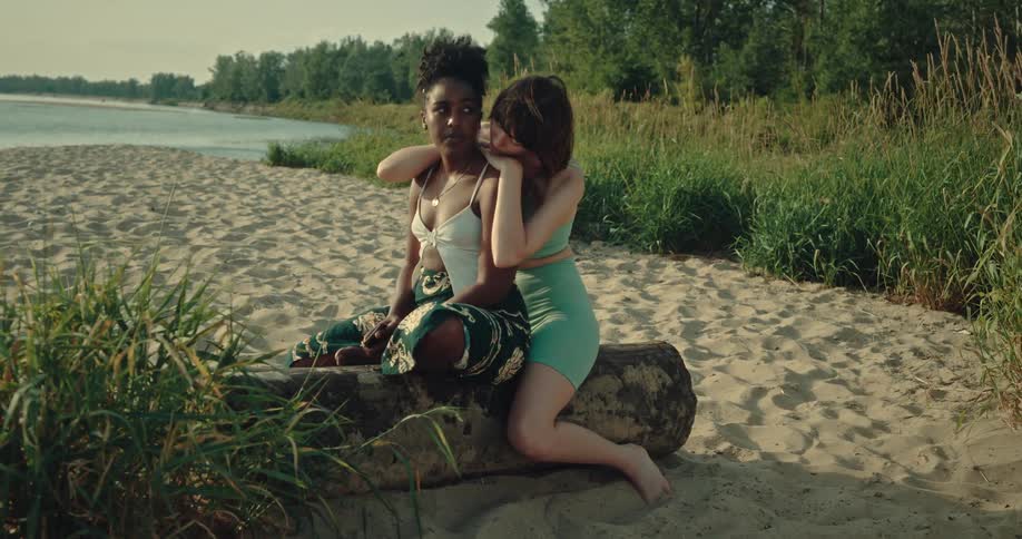 Two women hug on the log by the lake
