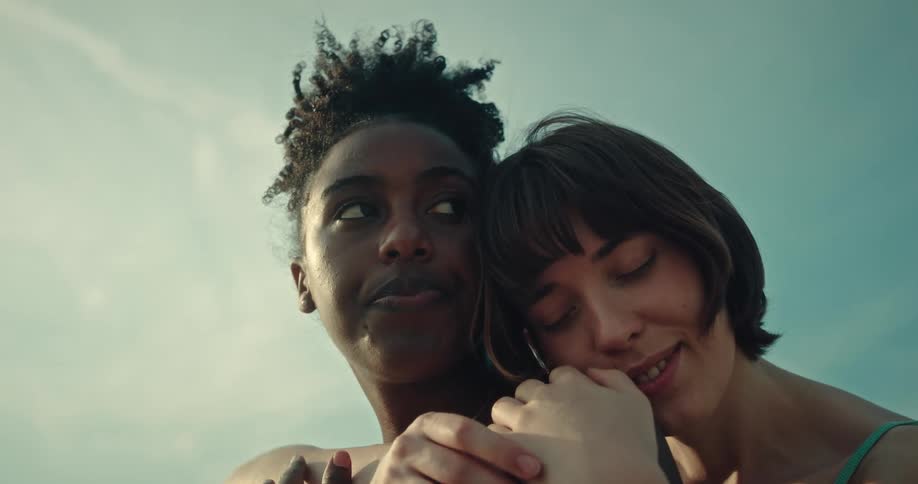 Woman affectionately hugging another woman from behind