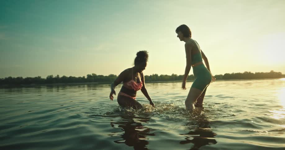 Two women are splashing each other in the lake