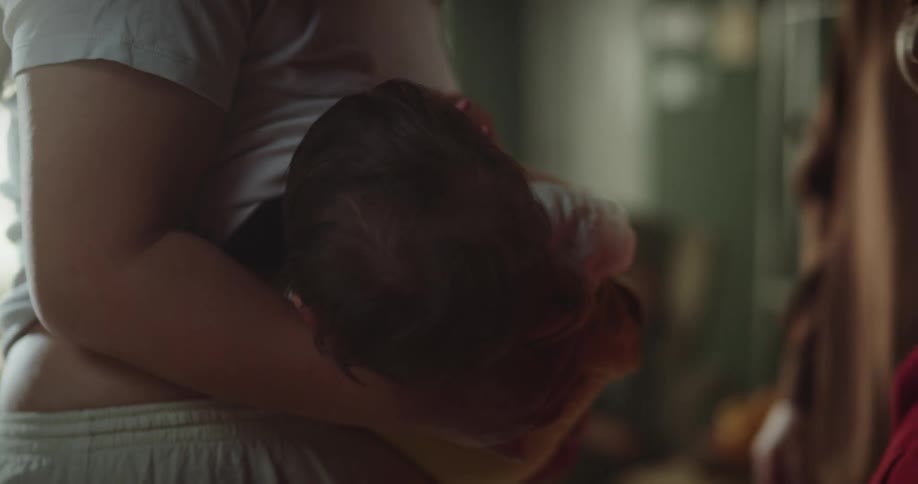 A mother breastfeeding her child while her greatgrandmother kisses her greatgrandson