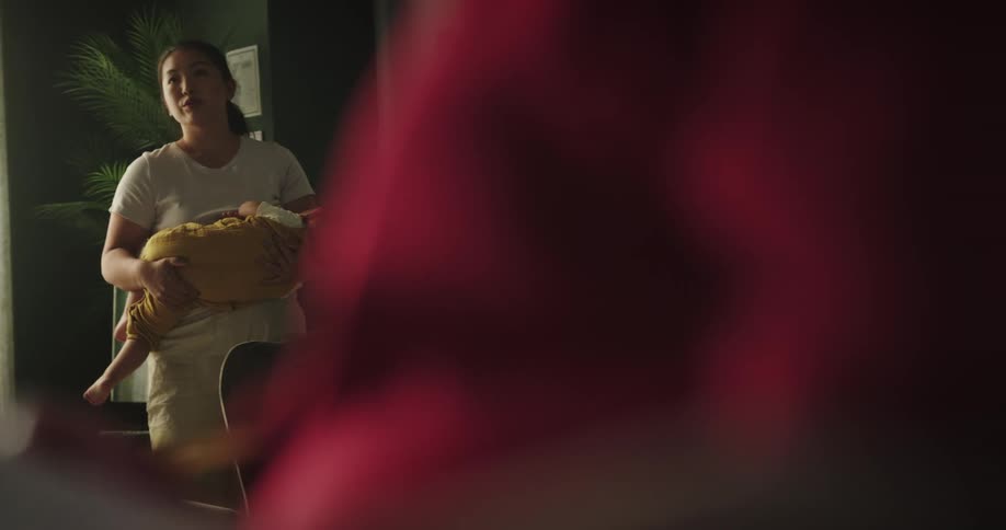 A hand shaking her son while a lady reads the news in the newspaper