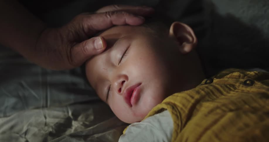 Grandmother rubs the forehead of her sleeping grandson