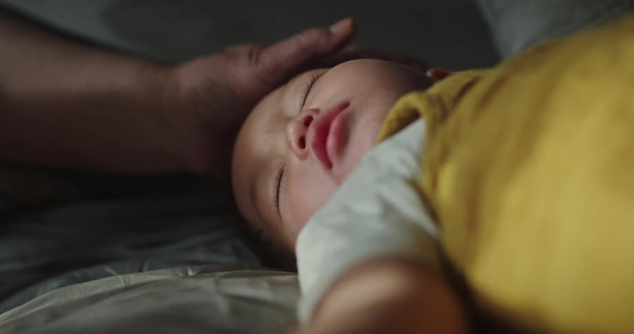Grandmother strokes head of sleeping grandchild