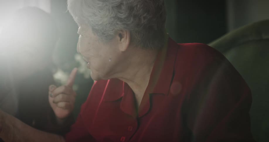 Grandmother offering a small orange to her granddaughter next to her daughter