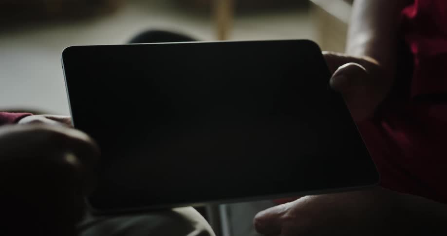 People sliding their fingers on a small tablet