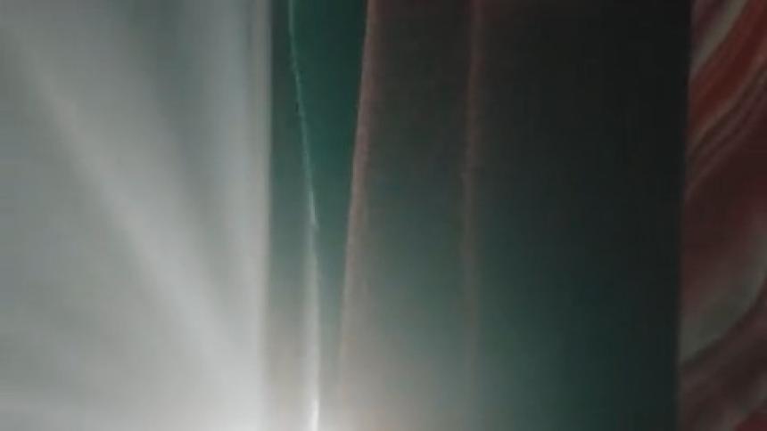 Bright light shines behind a row of fabrics swaying in the breeze