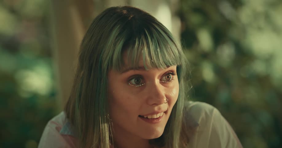 A woman smiles and nods as she converses with another person