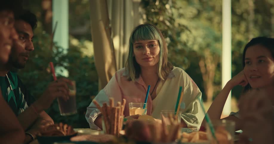 Friends sitting at a table with food and drinks conversing with each other