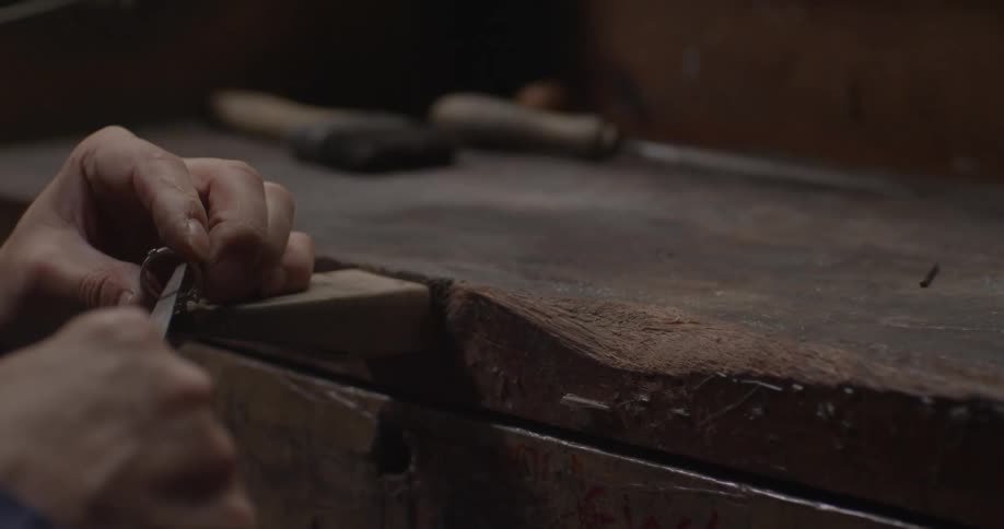 Hands holding a tool scrape the inside of a metal ring