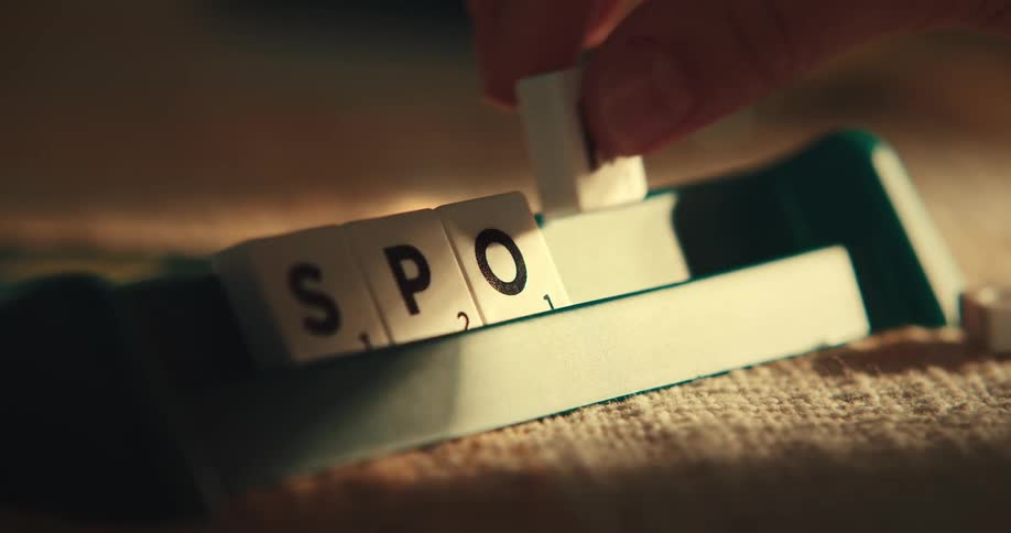 A human hand placing square blocks with letters on another object and forming a word