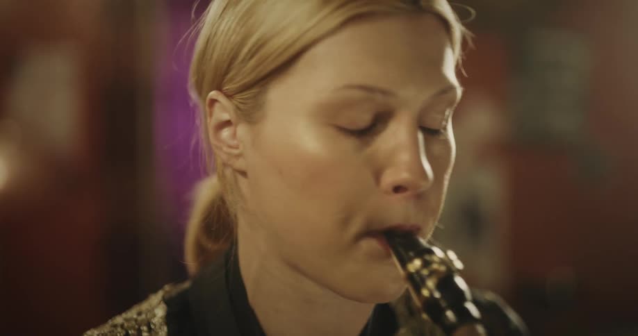 A lady playing saxophone in a room at night
