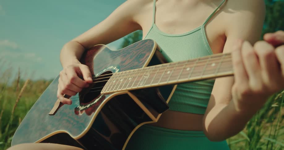 A woman is playing the guitar outdoors