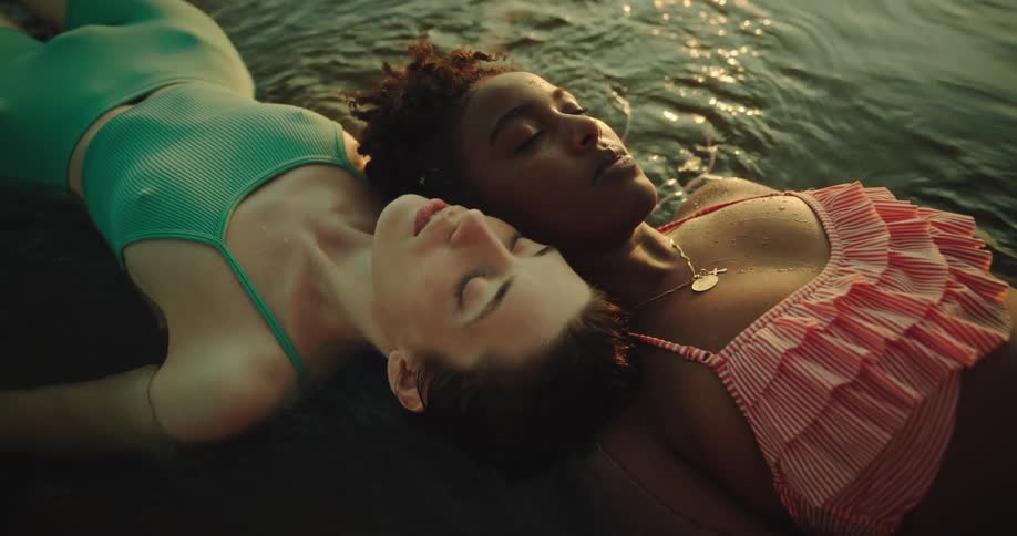 Two women wearing colorful swimsuits floating in water