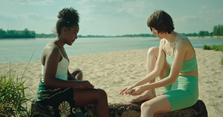 Two girls playing cards on the beach on a sunny day