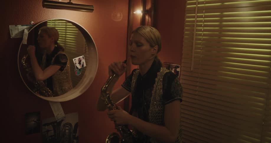 Young blonde woman adjusting and playing on a trumpet in indoor space