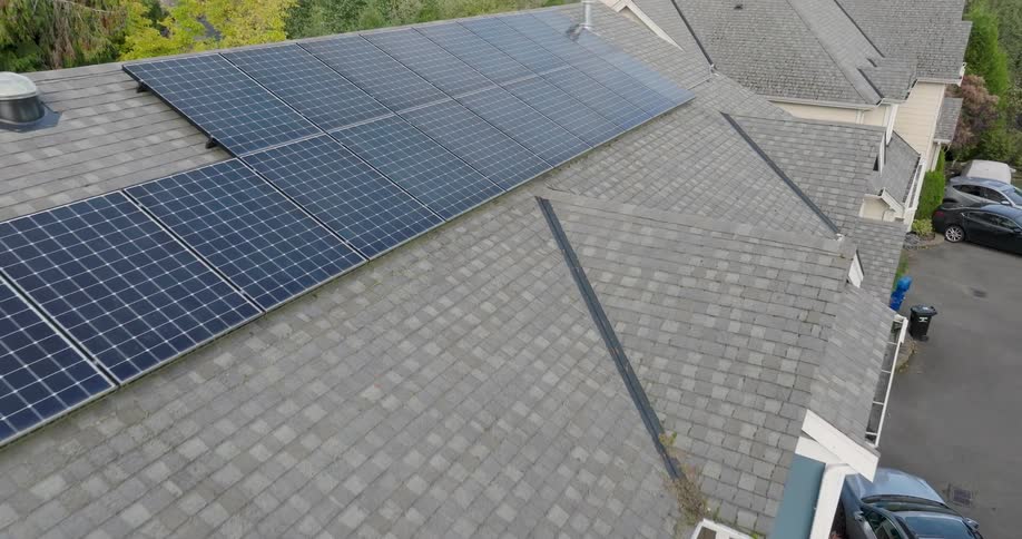 Descent from reflective solar panels to reveal they are on the roof of suburban neighborhood townhomes