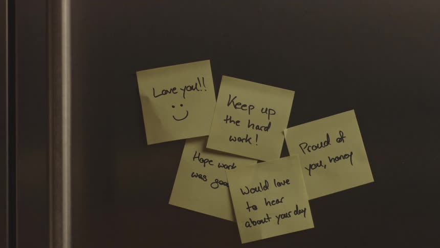 Teenage boy opens a refrigerator with postit notes on the front to pull out a drink