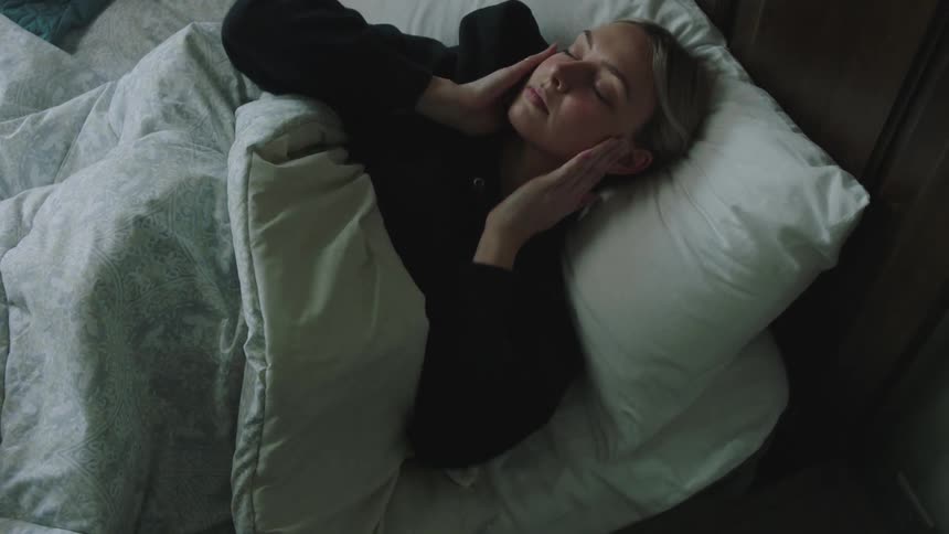 Woman waking up to a cellphone alarm and getting out of bed